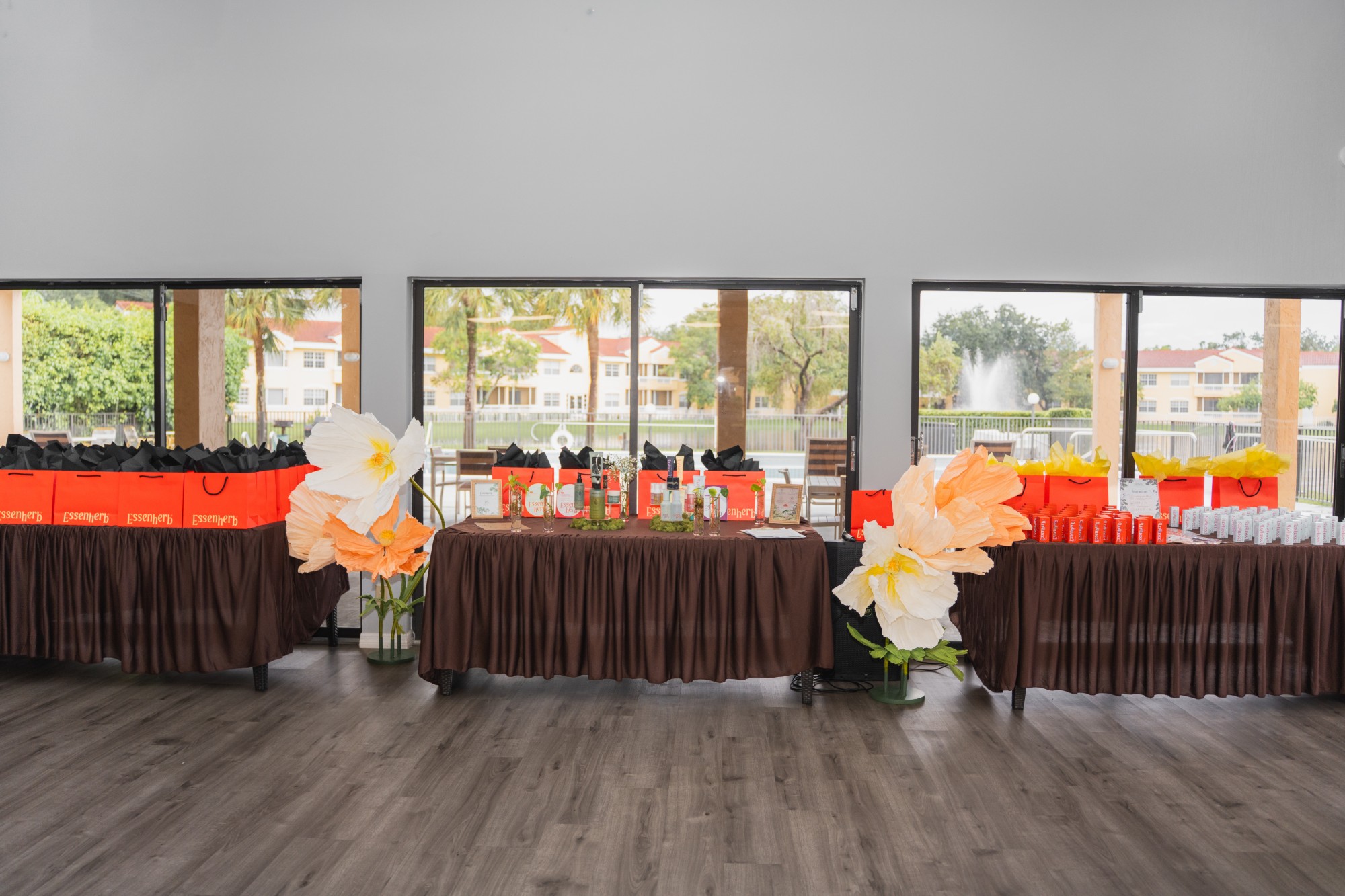 Wide ballroom shot with brown tables, orange gift bags and giant paper flowers