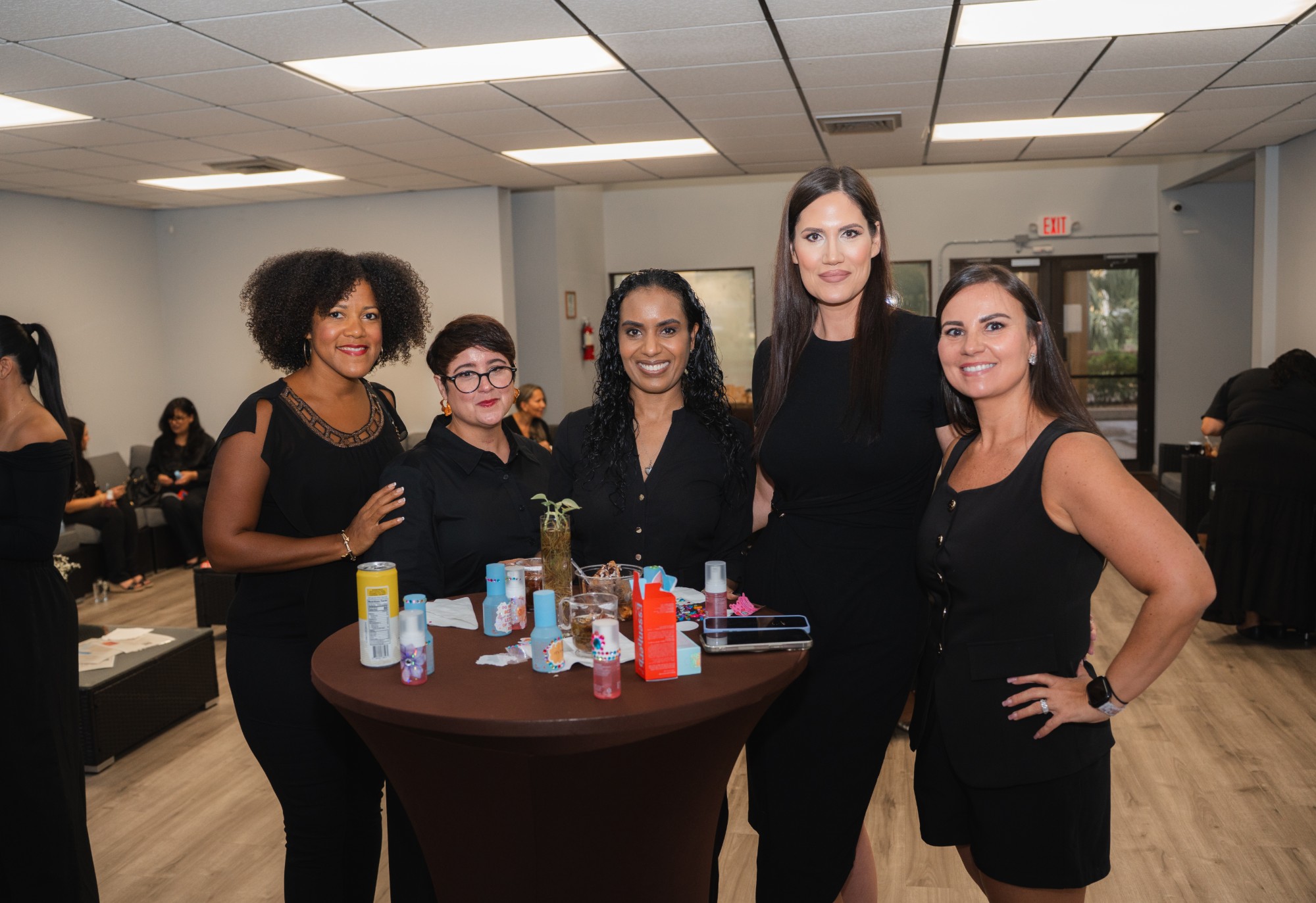 Five more guests gathered at a cocktail table with skincare samples