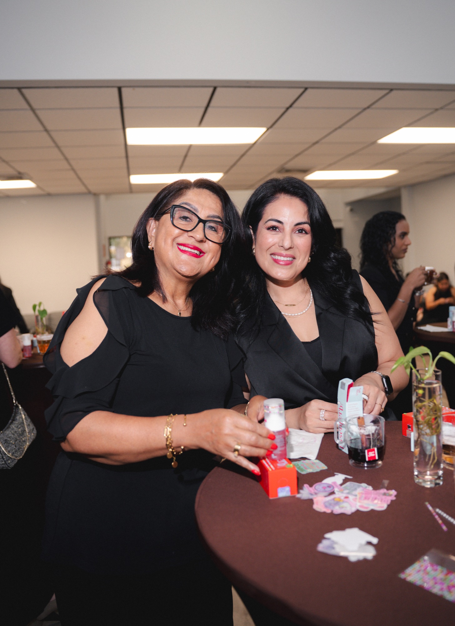 Two guests mingling at a cocktail table with skincare and drinks