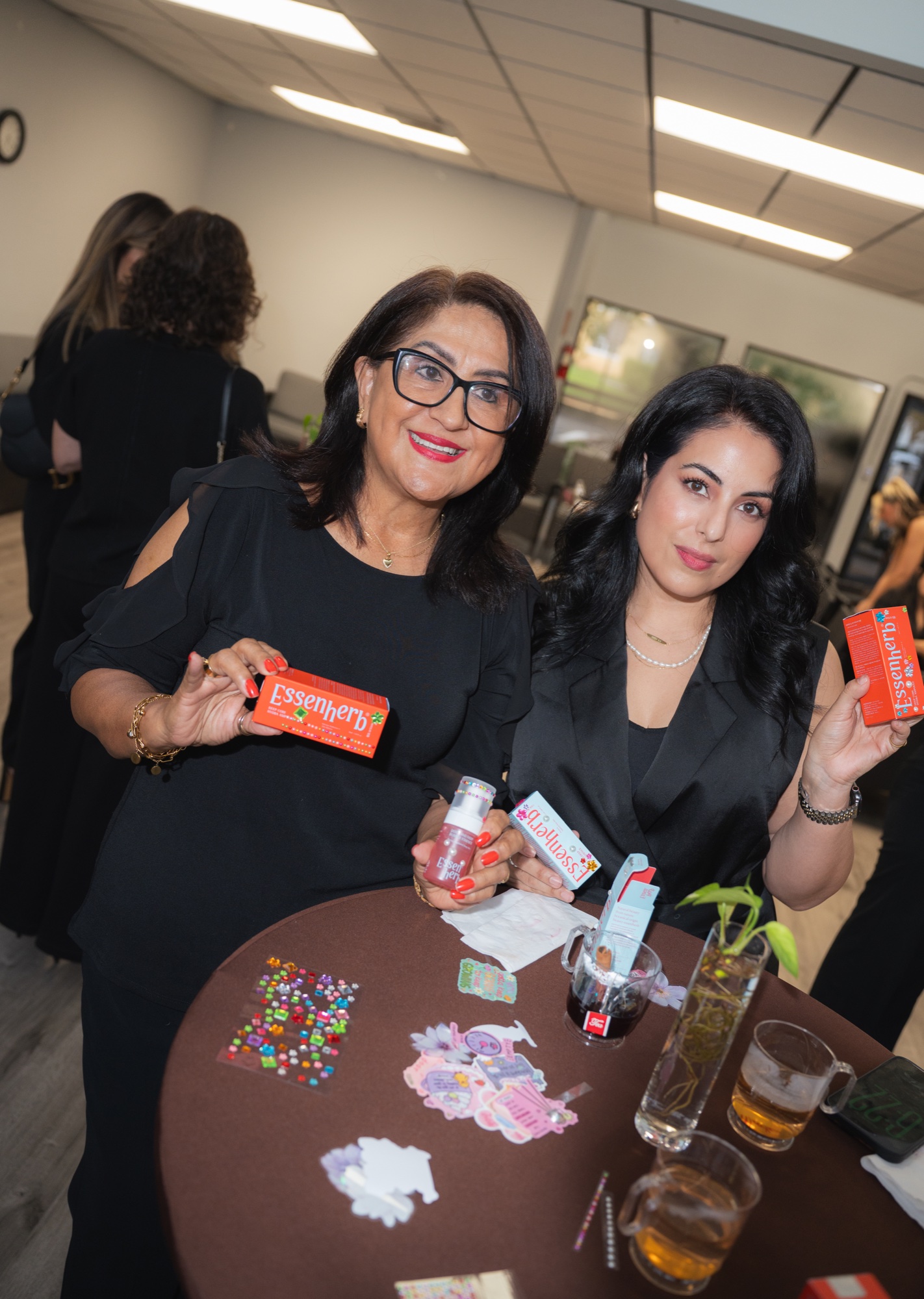 Two guests holding boxed skincare at a cocktail table