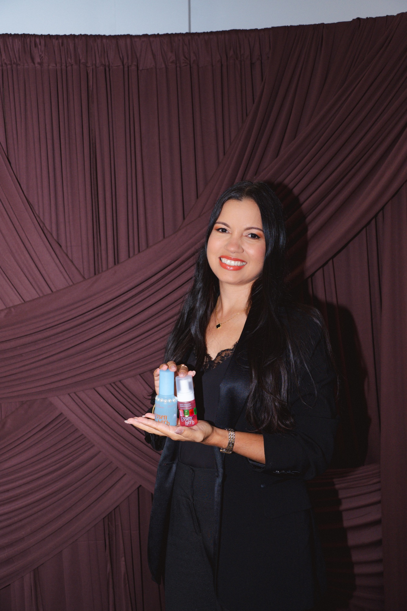 Guest posing at the backdrop with two skincare products