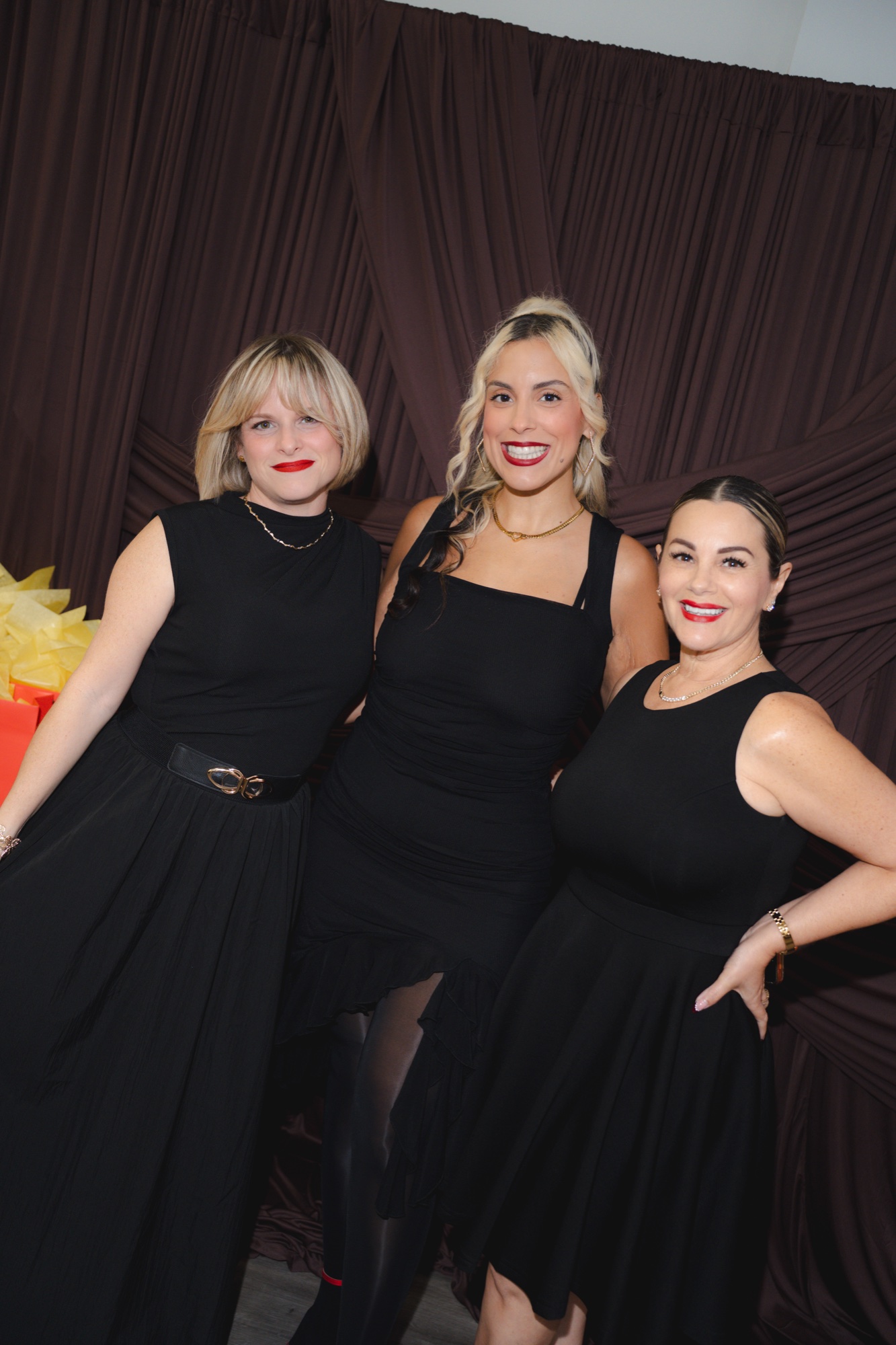 Three guests at the photobooth backdrop