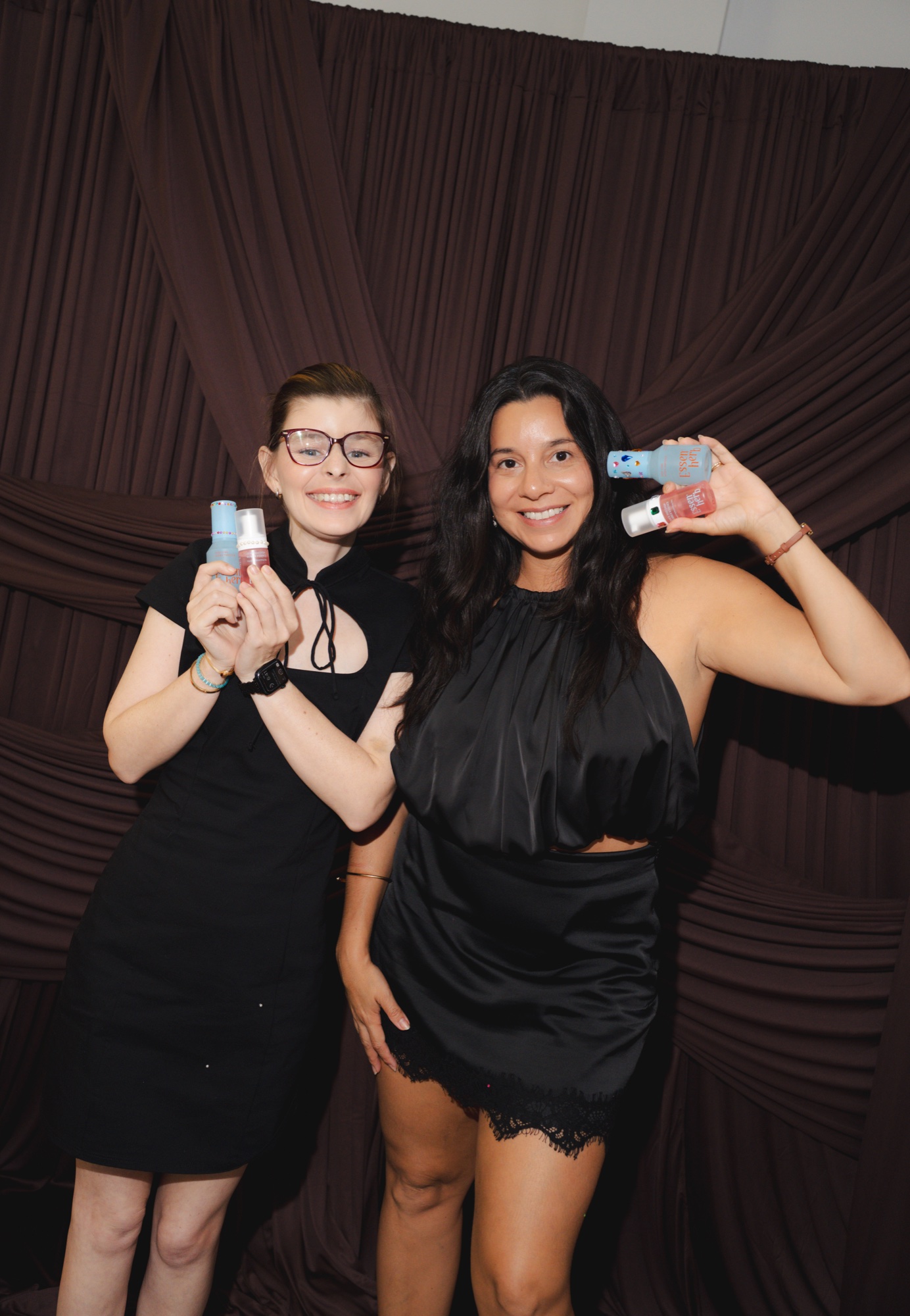 Two guests at the photobooth holding products