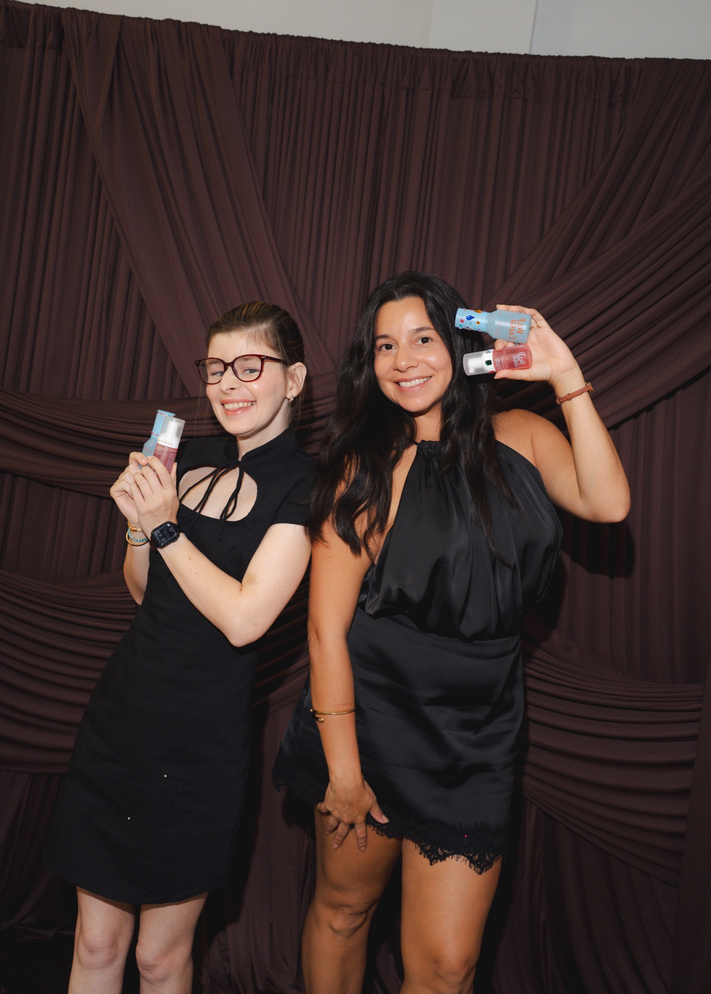 Two guests posing playfully with skincare at the photobooth