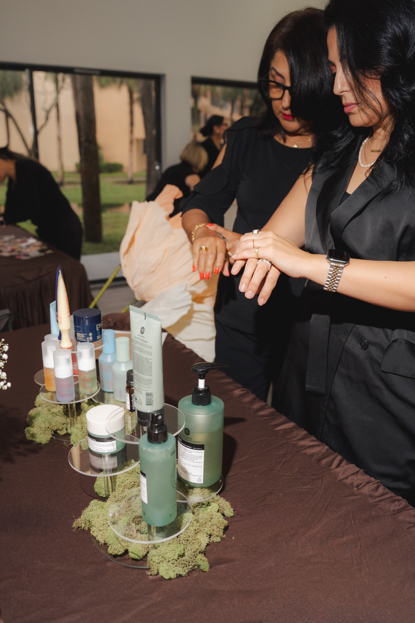Guests testing skincare products at the moss-covered display table