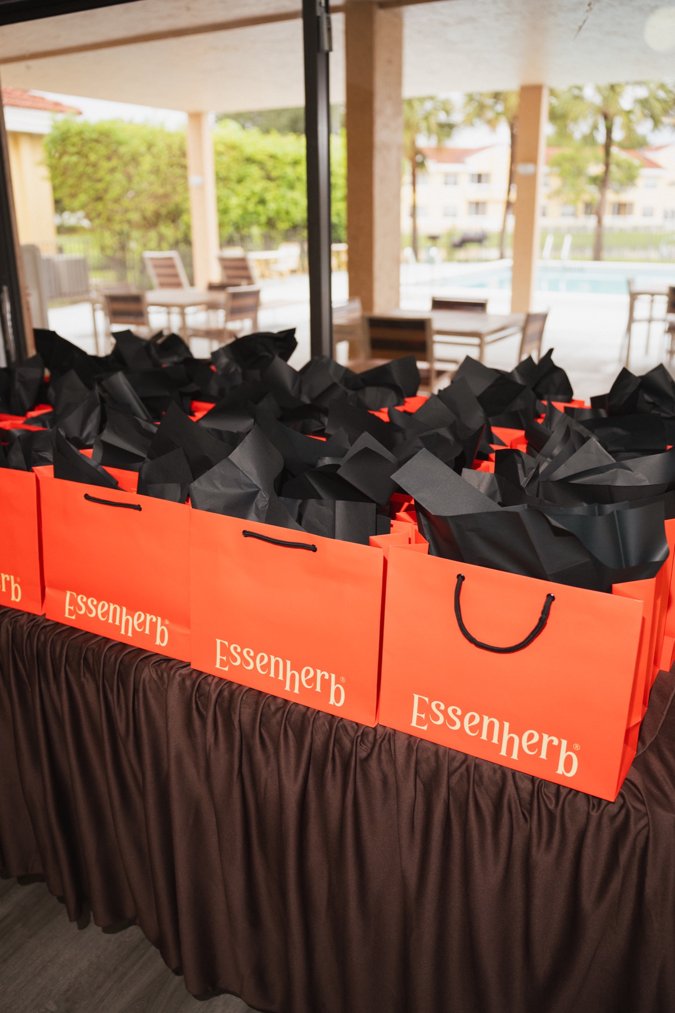 Rows of orange Essenherb gift bags on the brown-draped table