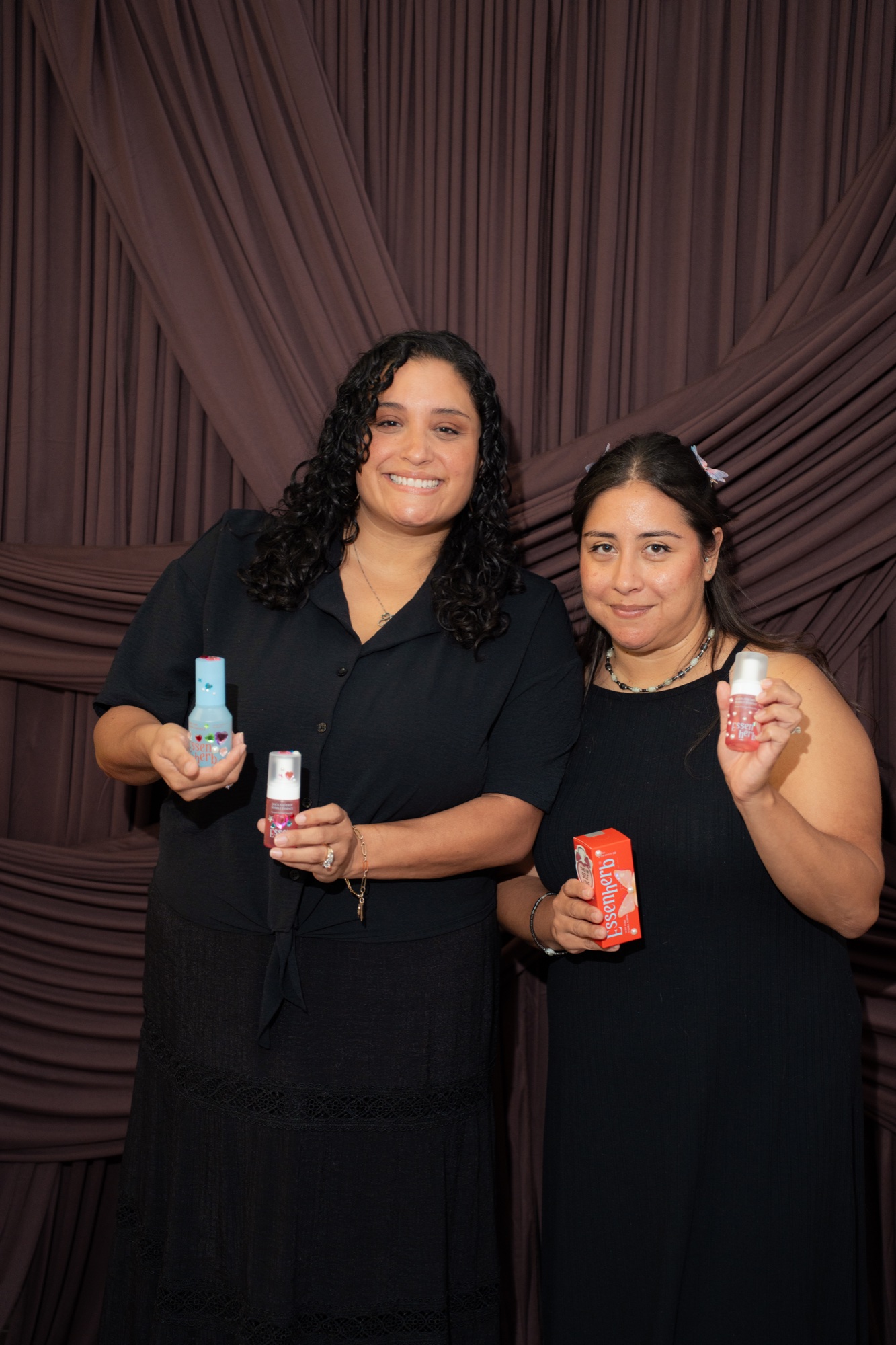 Two guests posing with skincare products at the photobooth